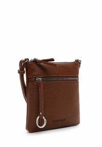 Hnědá kožená crossbody taška s texturovaným povrchem, přední kapsou na zip a dekorativním stříbrným kroužkem. Kompaktní obdélníkový tvar.