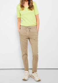 Ljusgrön t-shirt med korta ärmar, kombinerad med beige joggers med dragsko i midjan och sneakers i krämfärg. Avslappnad och lös passform.