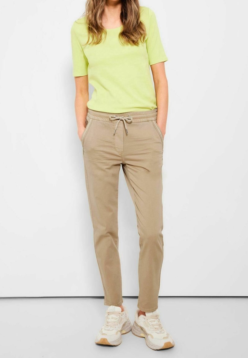 Ljusgrön t-shirt med korta ärmar, kombinerad med beige joggers med dragsko i midjan och sneakers i krämfärg. Avslappnad och lös passform.