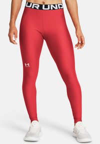 Crvene tajice s crnim pojasom na kojem je natpis "UNDER ARMOUR" i bijelim logotipom. Glatki, rastezljivi materijal, dizajn koji se prilagođava tijelu.