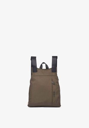 Mochila minimalista marrón con correas de hombro negras ajustables, asa superior, bolsillo delantero con cremallera y logo "KCB" en el lado derecho frontal.