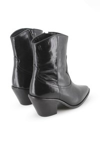 Botas de tobillo de cuero negro con punta afilada, tacón bajo y apilado, cremallera lateral y detalles de costura sutil. Textura suave y brillante.