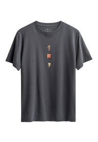 Grijze katoen T-shirt met een verticale afbeelding van een paperclip, een rode dobbelsteen en een tand, met een ronde hals en korte mouwen.