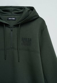 Sudadera con capucha de color verde oscuro con media cremallera, que presenta un logo en relieve "SALSA JEANS" en el pecho y detalles con cordón.