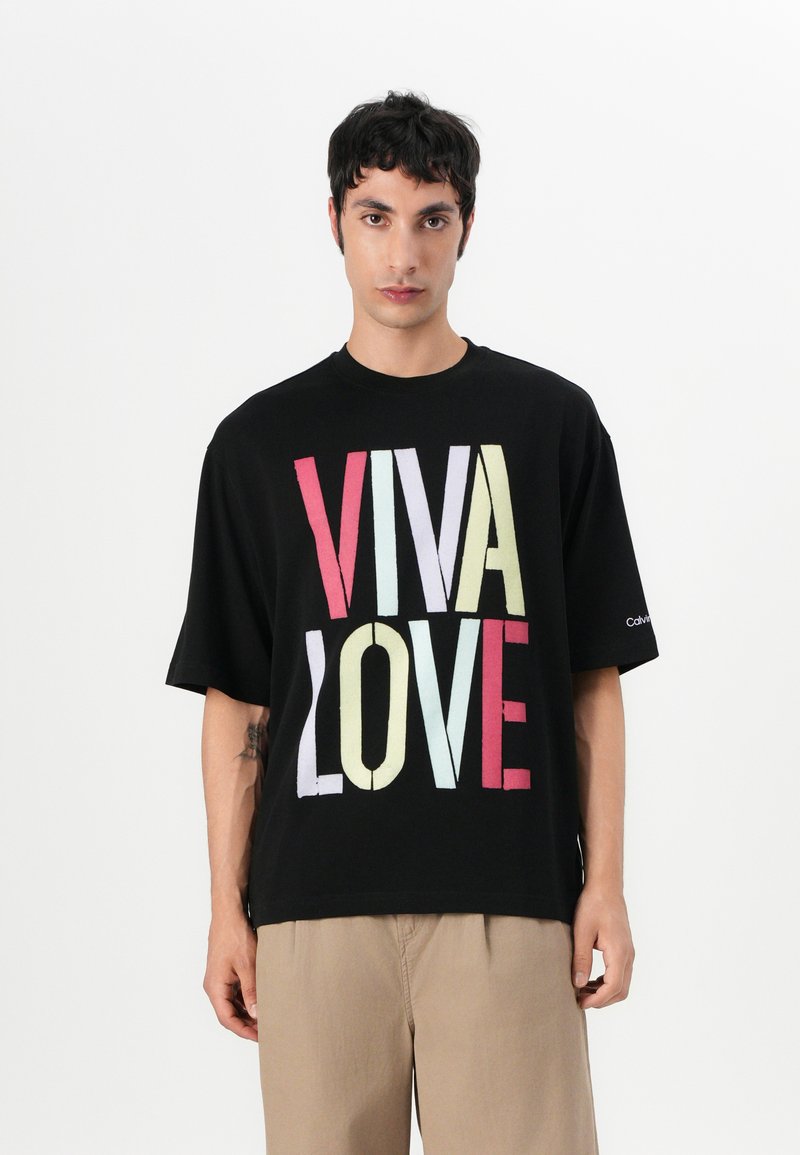Μαύρο βαμβακερό μπλουζάκι με μεγάλο πολύχρωμο κείμενο "VIVA LOVE". Κοντά μανίκια, άνετη γραμμή, στρογγυλή λαιμόκοψη, με διακριτική σήμανση στο μανίκι.