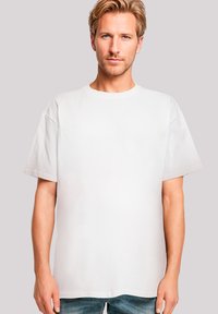 White cotton T-shirt with a relaxed fit, short sleeves, and a round neckline, paired with faded blue jeans.