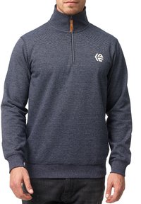 Marineblå zip-up sweatshirt med høj krave, der har et tekstureret mønster og et lille hvidt logo på brystet.