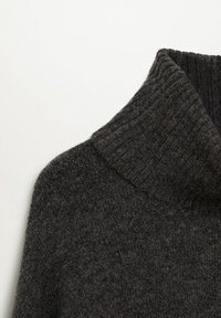 Pull gris foncé à col roulé côtelé avec un motif en maille texturée, vu de la zone de l'épaule et du col.
