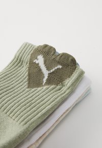 Meias verdes com nervuras, apresentando uma seção em forma de coração na cor verde-oliva com um logótipo branco. As cores adicionais incluem elementos em azul-claro e branco.