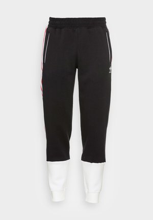 Pantalones de chándal negros con cintura elástica, bolsillos laterales y puños blancos. Presenta rayas rojas y blancas a lo largo de cada lado.