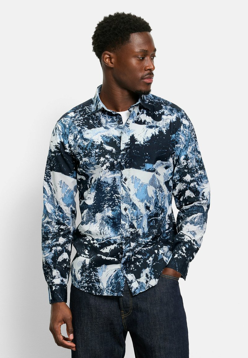 Hemd mit Knopfleiste, das ein blaues und weißes Bergmuster auf dunklem Hintergrund zeigt. Es besteht aus leichtem Stoff, hat lange Ärmel und einen Kragen.