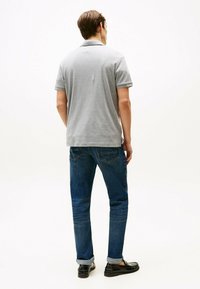 Grijs polo shirt voor heren met een klassieke kraag, gecombineerd met donkerblauwe denim jeans. De jeans hebben opgerolde mouwen en een vijf-pocket ontwerp.