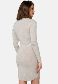 Robe ajustée à manches longues en tissu tricoté gris clair, avec un col rond et une texture subtile, se terminant au-dessus des genoux.