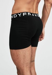 Svarta boxershorts i ett stretchigt tyg med en vit märkesresår. Designen framhäver formen med en åtsittande passform.