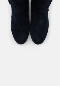 Mörkt marinblå mocka ankstövlar med rund tå och en mjuk textur, med en vikt manschett och minimal hårdvara för en elegant design.