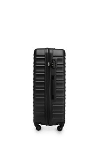 Valigia rigida nera con texture zigrinata, chiusura con zip, lucchetto integrato e quattro ruote per la mobilità. Dimensioni non specificate.