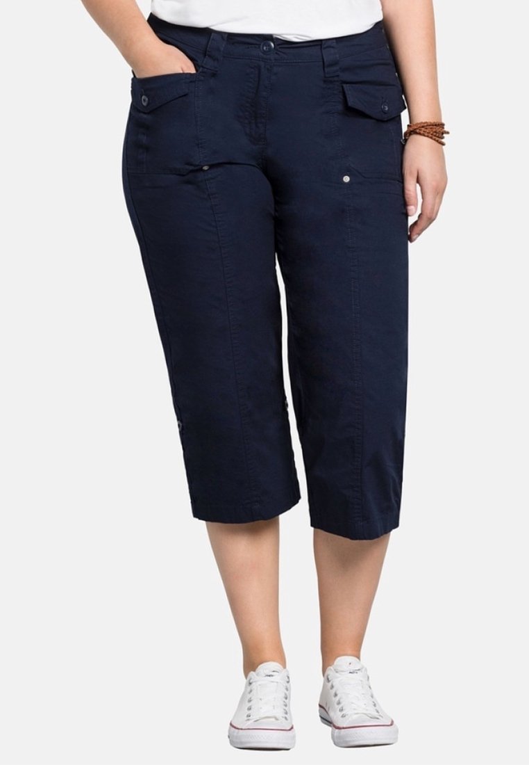 Pantaloni blu navy a vita alta realizzati in tessuto leggero, dotati di quattro tasche, dettagli con bottoni e orlo arrotolato, abbinati a sneakers bianche.