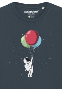 Marineblauwe t-shirt met een cartoon astronaut die drie ballonnen vasthoudt (rood, groen, blauw) tegen een sterrenachtergrond.