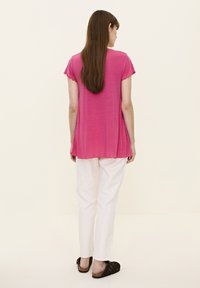 Top roz cu mânec�ă scurtă, cu margini ondulate, cu o croială lejeră, asortat cu pantaloni albi și încălțăminte maro. Design simplu, material ușor.