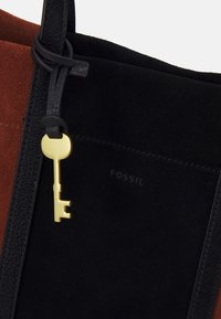 Borsa tote in suede nera e ruggine con un charm a forma di chiave dorata, caratterizzata da texture morbide e dettaglio del logo in rilievo sul lato.