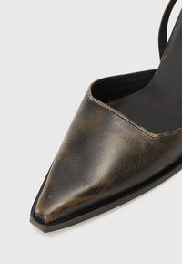 Ādas augstpapēžu kurpes ar smailu pirkstu, ar tumši bronzas apdari, elegantu dizainu un izgriezumu sānos, lai radītu mūsdienīgu izskatu.