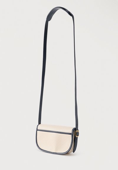 Μπεζ τσαντάκι χιαστί με μικρές μαύρες πουά, μαύρο περίγραμμα και ρυθμιζόμενο μαύρο λουρί με χρυσή αγκράφα.