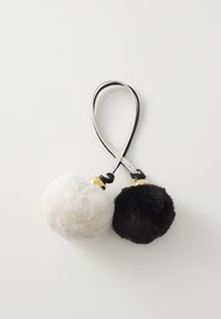 Keychain featuring two fur pom-poms, one white and one black, joined by a black and white strap with gold accents. Soft texture.