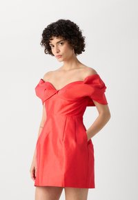 Červené off-shoulder šaty s priliehavým korzetom, drapovanými rukávmi, plisovanou sukňou a bočnými vreckami. Tkanina má hladký, lesklý povrch.