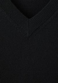 Gros plan d'un tissu tricoté noir montrant un col en V avec une texture côtelée autour de l'encolure.