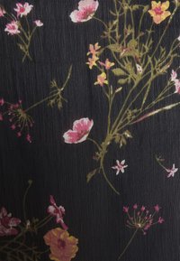 Tissu noir avec des motifs floraux dispersés en rose, jaune et blanc. La texture semble légèrement froissée avec une finition lisse.