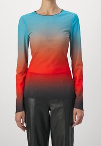 Maglietta a maniche lunghe con sfumature che vanno dal blu al rosso, con una texture liscia e scollo rotondo. Abbinata a pantaloni in pelle neri.