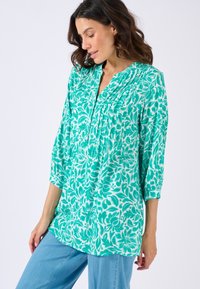 Groene bloemenblouse met driekwart mouwen, voorzien van plooien en een v-hals, gemaakt van een lichtgewicht stof met een gladde textuur.