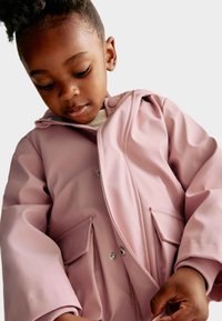 Světle růžová nepromokavá bunda s kapucí, patentkami a dvěma předními kapsami. Měkká textura s hladkým povrchem a žebrovanými manžetami.
