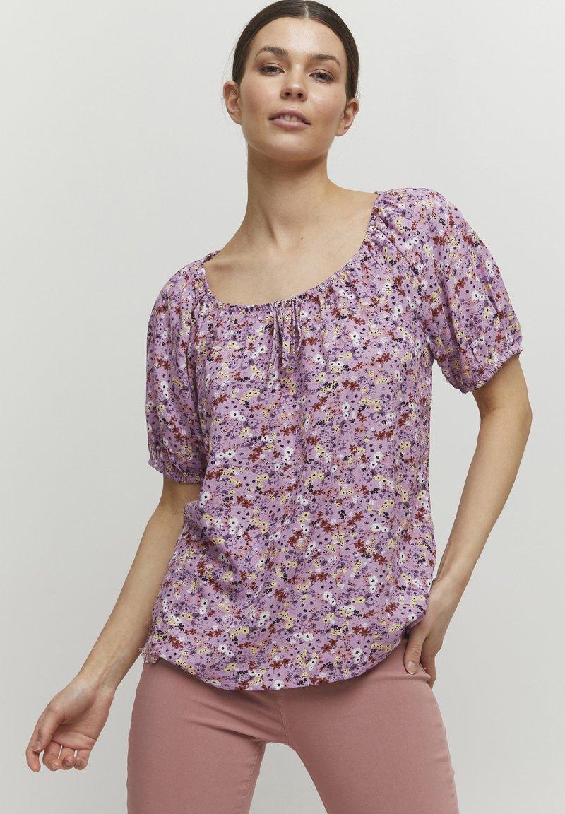 Blusa floral púrpura con mangas cortas abullonadas, escote fruncido y un corte holgado. Presenta pequeños patrones de flores multicolores en una tela suave.