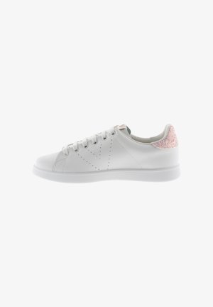 Zapatilla blanca de cuero con detalles perforados, puntera redonda, suela plana y un acento texturizado rosa en el talón. Cordones en blanco a juego.