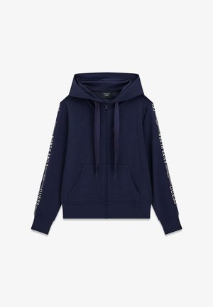 Sudadera con capucha azul marino, cremallera completa, bolsillos frontales, capucha con cordón y texto blanco "North Sails" y "Guess" a lo largo de las mangas.