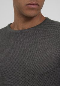 Grijs gebreid sweater met een ronde halslijn, met een textuur en een dichtgeweven patroon. De stof is zacht en flexibel, ideaal om te lagen.