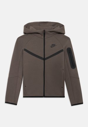 Nike dukserica s kapuljačom u tamno smešnoj boji, sa zatvaračem, kutevim crnim akcentima i džepom sa zatvaračem na ruci. Mekana, teksturirana tkanina.