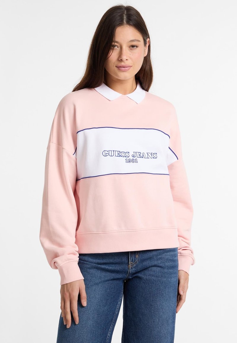 Sudadera rosa con un panel blanco que presenta "GUESS JEANS 1981" bordado en azul. Mangas largas con puños de canalé. Diseño de cuello clásico.