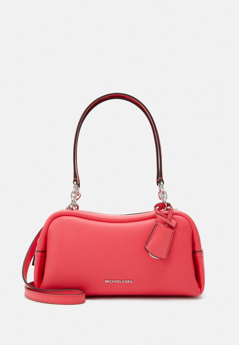 Sac à main en cuir rouge avec un design incurvé, une quincaillerie argentée, une courte bandoulière et une étiquette amovible portant le nom de la marque "MICHAEL KORS".