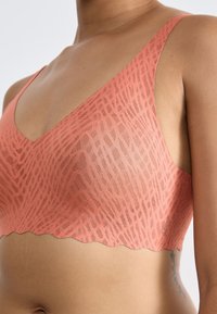 Soutien-gorge color pesca con un motivo testurizzato, design a scollo a V e bordi ondulati. Realizzato in tessuto leggero per il massimo comfort.