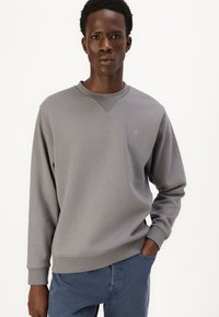 Grauer Pullover mit rundem Halsausschnitt und gerippten Bündchen. Glatte Textur, mit einem kleinen Logo auf der linken Brust und einem lässigen Schnitt.