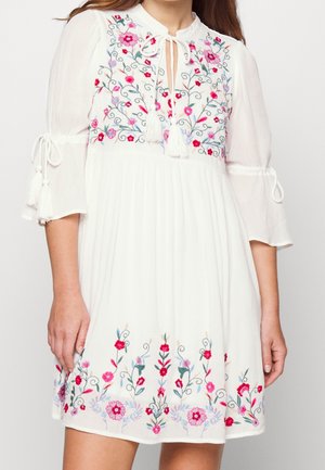 Biała sukienka z różowo-czerwonym kwiatowym haftem na dekolcie i dole, rękawy do łokcia z wiązanymi detalami oraz dekolt z wycięciem na przodzie z chwostami.