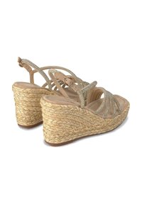 Sandali con zeppa con base in paglia intrecciata, soletta color beige e cinturini metallici incrociati per un tocco di dettaglio e supporto.