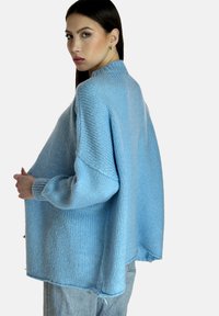 Maglione oversize azzurro chiaro in knit con spalle scese, colletto alto e tessuto texturizzato. Vestibilità ampia con spacchi laterali al fondo.