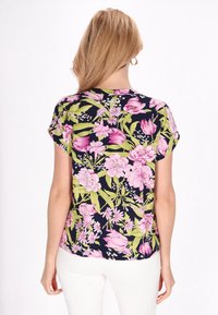Bluse med kort ærme og blomsterprint i marineblå, med pink og grønne blomster, letvægtsstof og en buet kant.