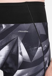 Leggings neri e grigi con un motivo geometrico, realizzati in tessuto elasticizzato con vita elastica e logo "climalite".