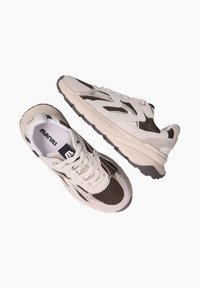 Beige en bruine mesh sneakers met een vetersluiting, voorzien van een textuur bovenkant, een verzachte zool en contrasterende accenten.