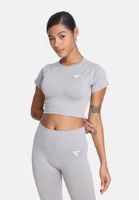 Szary crop top i dopasowane legginsy z wysokim stanem w teksturowanym materiale. Obydwa elementy mają biały logo. Gładki, dopasowany krój.