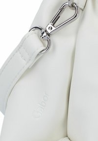 Weiße Lederhandtasche mit glatter Textur, ausgestattet mit einem silbernen Metallverschluss und einer Logo-Prägung. Der Tragegurt weist sichtbare Nähdetails auf.